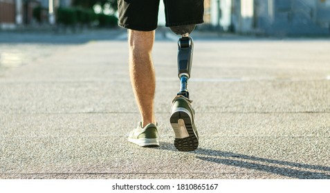 Low angle view at disabled young man with prosthetic leg walking along the street - Powered by Shutterstock