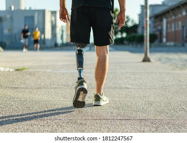 Low angle view at disabled young man with prosthetic leg walking along the street - Shutterstock ID 1812247567