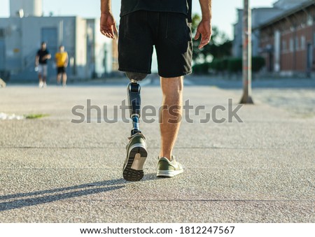 Low angle view at disabled young man with prosthetic leg walking along the street Foto d'archivio © 