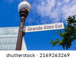 Low angle view of Grande-Allée East sign on street light with building in soft focus background, Quebec City, Quebec, Canada
