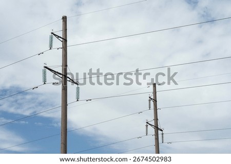 Low angle view of electrical power transmission pole with green glass insulators and crossbeams against cloudy sky. High voltage distribution infrastructure