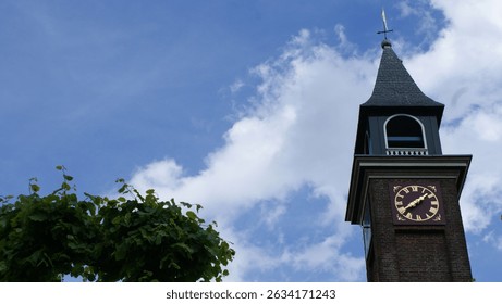 low angle view of an elegant tower of a church, possibly The Church of the Holy Trinity, featuring a classic clock and spire, set against a bright blue sky with fluffy clouds.