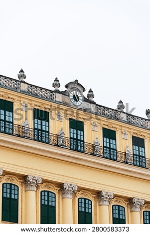 Low angle view of the elegant yellow facade and Baroque architecture of Schonbrunn Palace under a clear sky.
