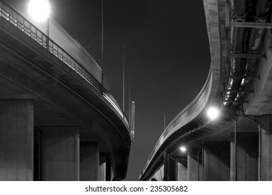 Low angle view of elevated road in black and white at night
