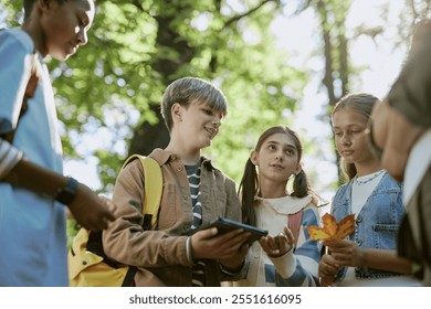 Low angle view of ethnically diverse teen boys and girls discussing plants during tour in botanical garden