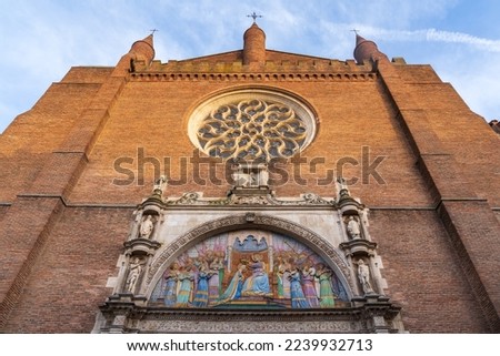 Low angle view of the facade of ancient Notre Dame de la Dalbade church with rosette and polychrome tympanum representing the Coronation of the Virgin Mary with angels, Toulouse, France