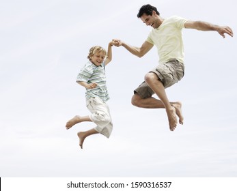 Low Angle View Of Father And Son Jumping