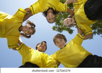 Low Angle View Of Female Football Team Forming Huddle Against Clear Sky