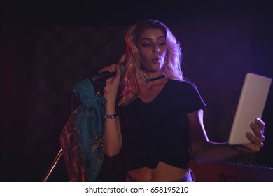 Low angle view of female singer taking selfie with digital tablet in nightclub - Powered by Shutterstock