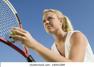 Low angle view of a female tennis player preparing to serve against clear blue sky - Powered by Shutterstock