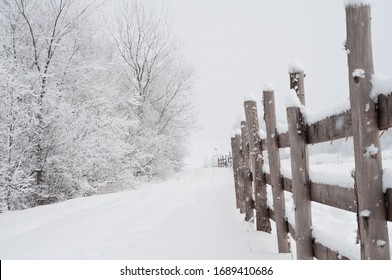 Low angle view of a festive winter wonderland snow-covered landscape, path and wooden fence.
