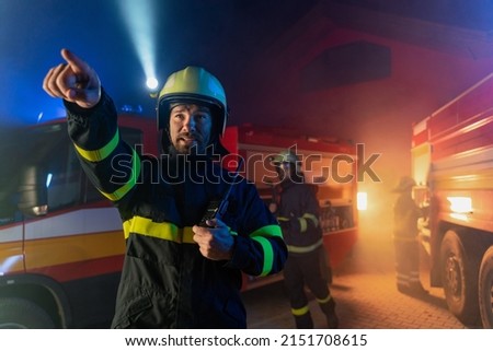 Low angle view of firefighter with fire truck in background at night.
