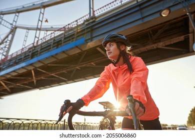 Low Angle View Of Fit Young 20s Caucasian Woman Sportswoman On Bike Enjoy Active Weekend Cycling. Happy Millennial Gen Z Female Cyclist In Helmet Sportswear Cycle Ride Bicycle. Sport, Healthy Life.