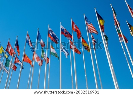 low angle view of flags of various UN members fluttering on wind against cloudless blue sky