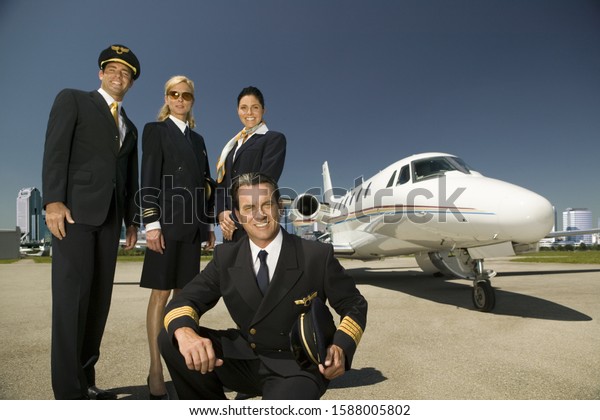 Low angle view of flight crew standing next to\
airplane on tarmac