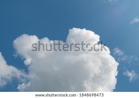 Low angle view of fluffy cumulus clouds against blue sky background.