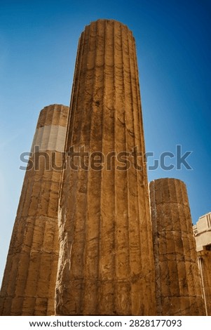 Low angle view of fluted ancient Greek marble Doric columns rising against a blue sky.