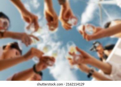 Low Angle View Of Friends Having Fun At Poolside Summer Party, Clinking Glasses With Colourful Summer Cocktails Near Hotel Swimming Pool. Blurred Background Concept