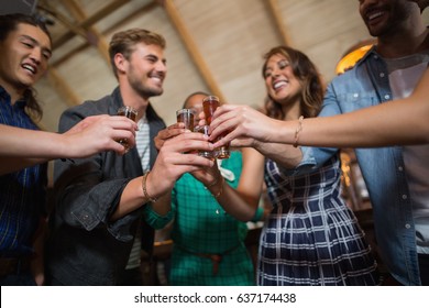 Low angle view of friends toasting shot glasses in bar