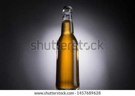 low angle view of glass bottle with beer on dark background with back light