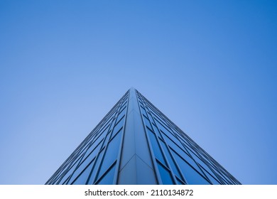 Low angle view of glass facade of tall office building against clear blue sky