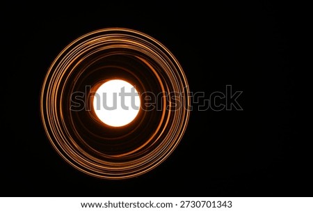 Low angle view of a glowing round light bulb inside a ribbed glass fixture creating golden concentric circles against a pitch-black background. This abstract minimalist composition represents innovation, bright ideas, focused energy, and modern interior design. Perfect for use as a dramatic wallpaper or conceptual backdrop.