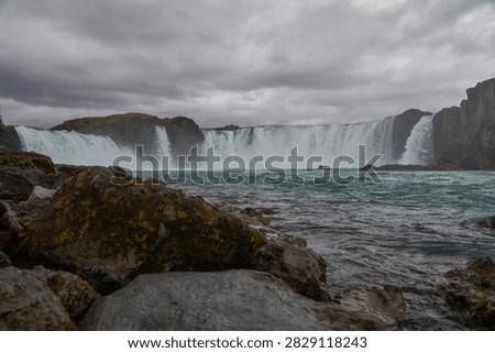 Low angle view of Godafoss waterfall from rocky shoreline - North Iceland