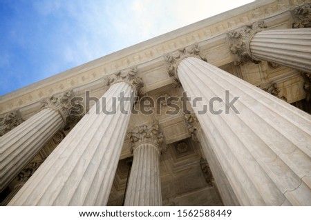 Low angle view of grand classical stone columns soaring up to decorative entablature at a Court building in Washington DC, USA