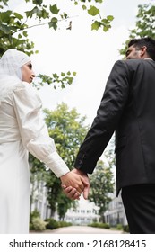 low angle view of groom and muslim bride holding hands