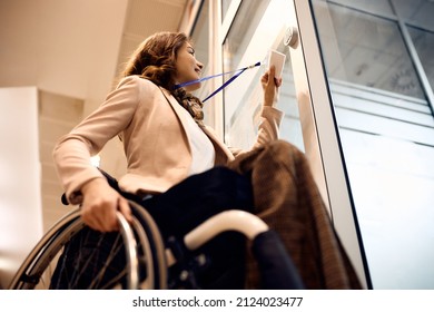 Vista de ángulo bajo de una mujer de negocios feliz con discapacidad usando la llave de la tarjeta para abrir la puerta de la oficina.