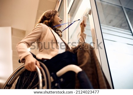 Low angle view of happy businesswoman with disability using card key to unlock office door.