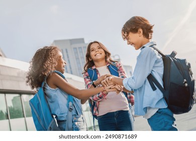 Low angle view of happy diverse multiethnic elementary middle school kids children pupils classmates friends boys and girls are holding hands together at the street showing unity and teamwork - Powered by Shutterstock