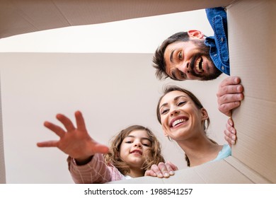 Low Angle View Of Happy Family Opening Cardboard Box Together And Unpacking Belongings.