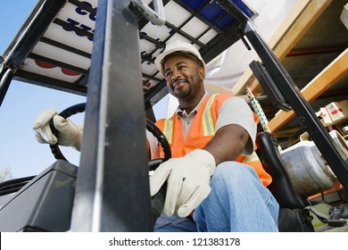 Low Angle View Of A Happy  Male Industrial Worker Driving Forklift At Workplace