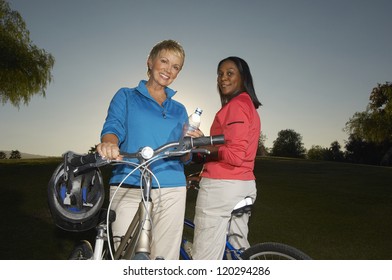 Low angle view of happy multiethnic female friends with bicycle