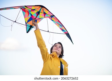 Low angle view of happy preteen girl preparing kite for flying outdoors.