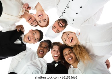 Low Angle View Of Happy Restaurant Staff Standing Against White Background