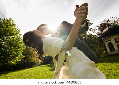 Low angle view of happy young newlywed couple dancing outdoors in sunlight. - Powered by Shutterstock