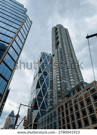 Low angle view of Hearst Tower skyscraper in Manhattan. Architectural shot of the Hearst Tower triangular steel frame and glass facade under a cloudy sky in New York City.