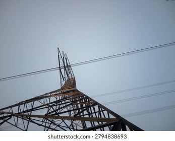 Low angle view of high voltage electric tower in the left with clear gradient sky background, copy space on the right side