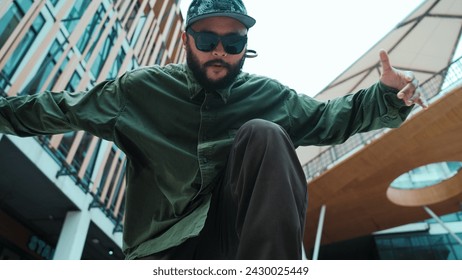 Low angle view of hipster pose in hip hop style surrounded by mall view. Portrait of sporty asian hip hop choreographer dancing break dance while looking at camera. Outdoor sport 2024. Endeavor. - Powered by Shutterstock