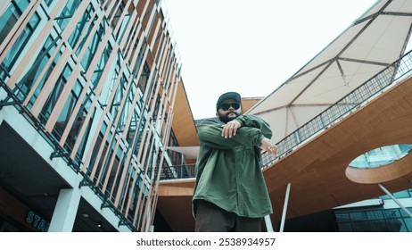 Low angle view of hipster pose in hip hop style surrounded by mall view. Portrait of sporty asian hip hop choreographer dancing break dance while looking at camera. Outdoor sport 2024. Hiphop. - Powered by Shutterstock