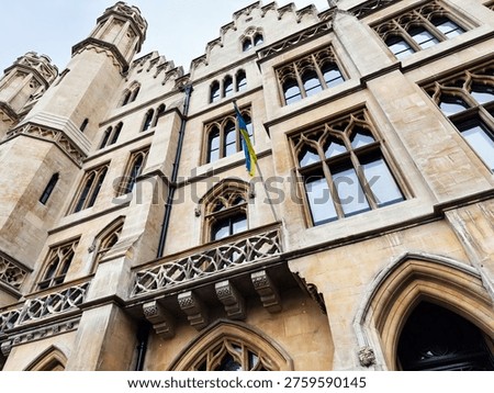 Low angle view of a historic Gothic revival stone facade with arched windows and ukrainian  flag in London, UK.