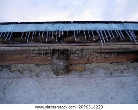 Low angle view of icicles hanging from roof of old rustic barn.