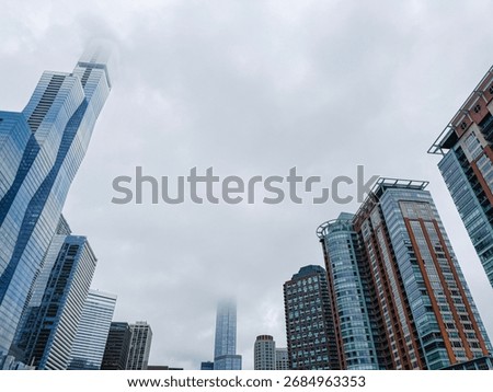 Low angle view of iconic urban architecture in downtown Chicago. Low clouds envelop the top of the skyscraper buildings.