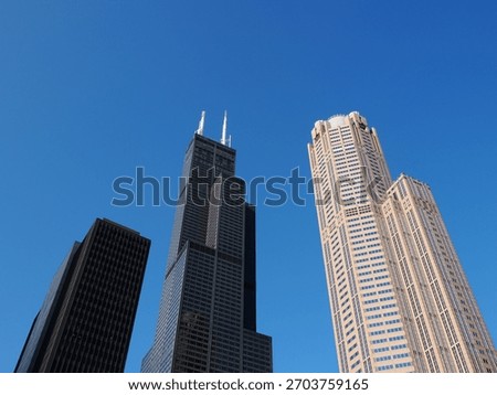 Low angle view of the imposing Willis Tower and the curved 333 West Wacker Drive skyscraper against a clear sky.