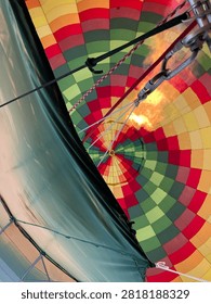 Low angle view inside colorful hot air balloon envelope being inflated with bright propane burner flame, extreme outdoor adventure background
