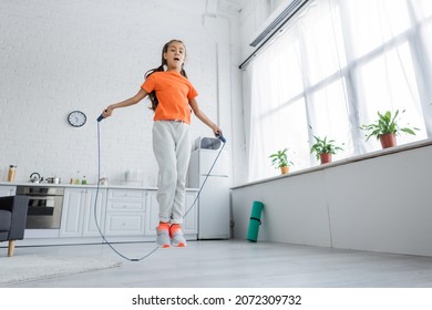 Low Angle View Of Kid Jumping With Skipping Rope In Kitchen