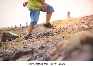 Low Angle View Of Kid Legs Walking Up The Hill Against Bright Sky
