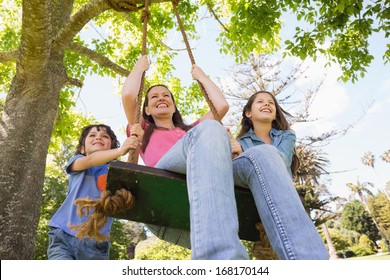 Low Angle View Of Kids Pushing Mother On Swing In Playground